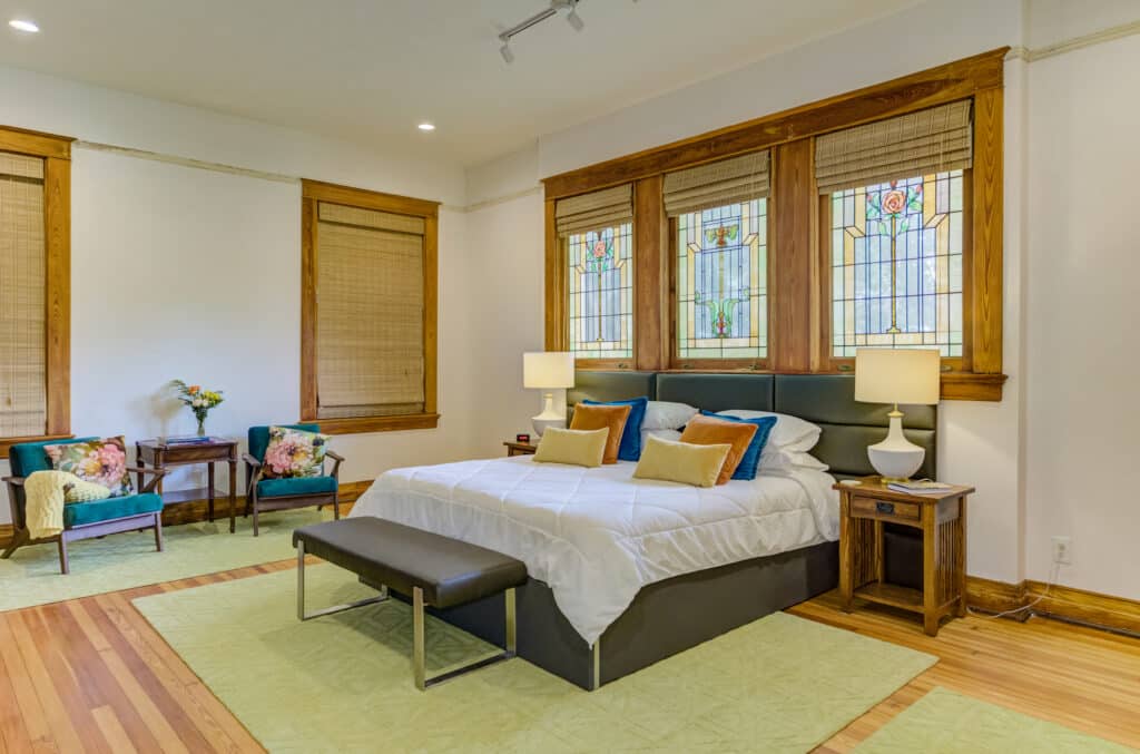 The Fannie Suite with King Bed, original stained glass windows, and seating area at our Mississippi Bed and Breakfast, Oak Hall.